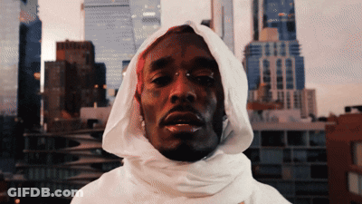 A Man Wearing A White Hooded Sweatshirt With A City Skyline In The Background GIF