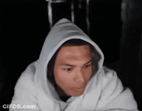 A Man Wearing A White Hoodie Looks At The Camera GIF