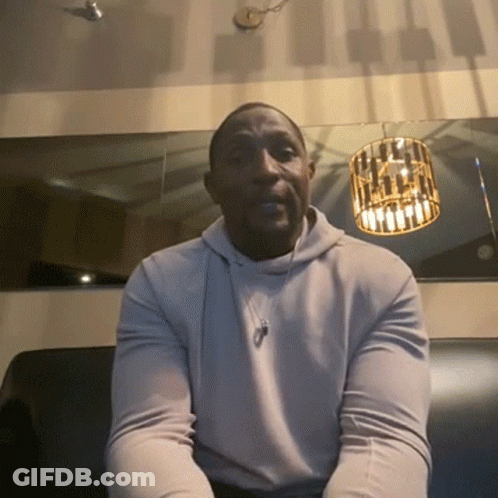 A Man Wearing A White Hoodie Sits On A Couch GIF