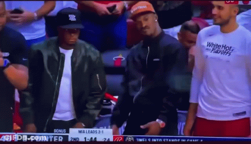 A Man Wearing A White Hot Playoffs Shirt Is Standing In The Stands During A Basketball Game GIF
