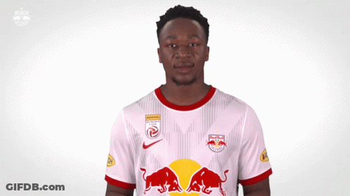 A Man Wearing A White Jersey With Red Bulls On The Front GIF