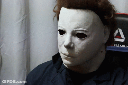 A Man Wearing A White Mask Is Sitting In Front Of A Gaming Monitor GIF