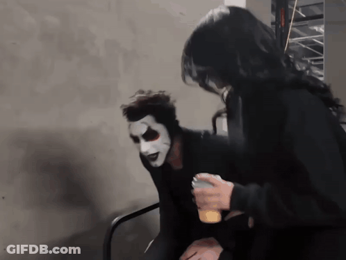 A Man Wearing A White Mask Is Sitting Next To A Woman GIF