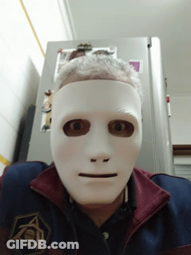 A Man Wearing A White Mask Is Standing In Front Of A Fridge That Has A Picture Of A Cat On It GIF