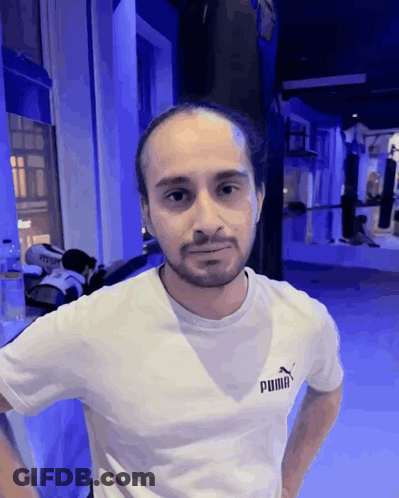 A Man Wearing A White Puma T-Shirt Stands In A Gym GIF