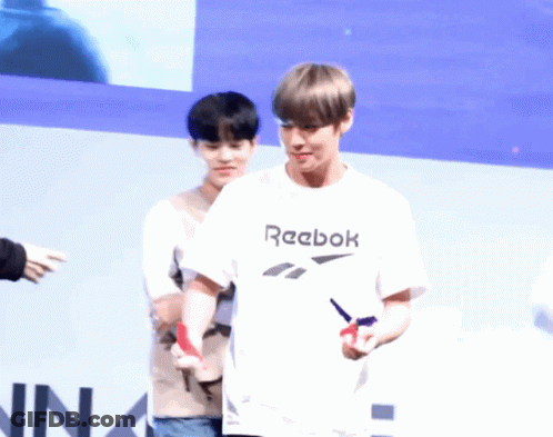 A Man Wearing A White Reebok T-Shirt Stands Next To Another Person GIF