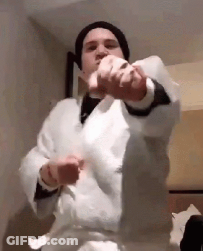 A Man Wearing A White Robe And A Black Hat Is Holding A Piece Of Paper In His Hands . GIF