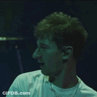 A Man Wearing A White Shirt And A Chain Around His Neck GIF