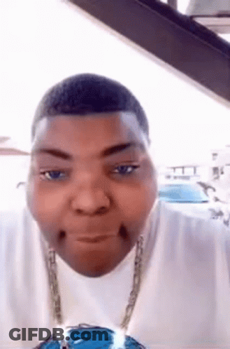 A Man Wearing A White Shirt And A Chain Is Making A Funny Face . GIF