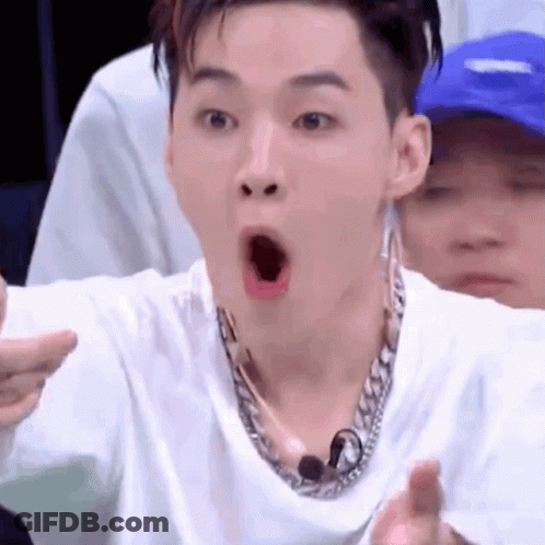 A Man Wearing A White Shirt And A Chain Necklace Is Making A Funny Face . GIF
