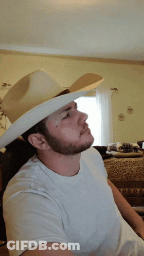 A Man Wearing A White Shirt And A Cowboy Hat Makes A Peace Sign GIF
