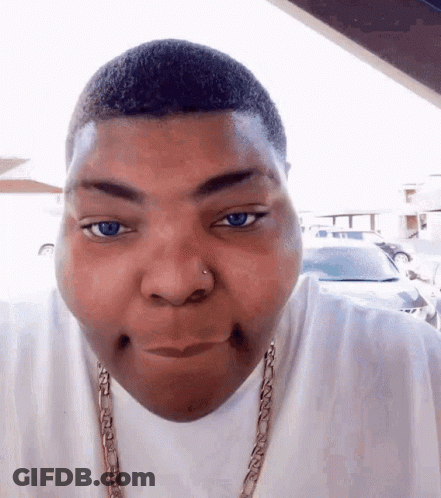 A Man Wearing A White Shirt And A Gold Chain Is Making A Face GIF