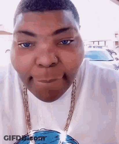 A Man Wearing A White Shirt And A Gold Chain Is Making A Face . GIF