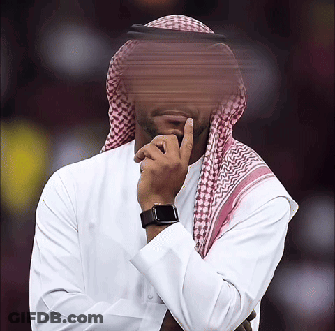 A Man Wearing A White Shirt And A Head Scarf Holds His Hand To His Chin GIF