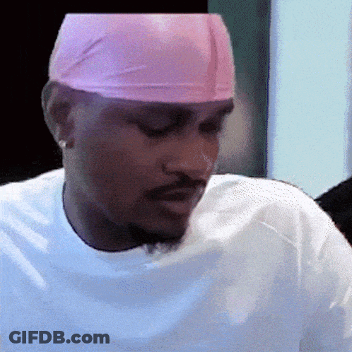 A Man Wearing A White Shirt And A Pink Headband Looks Down GIF