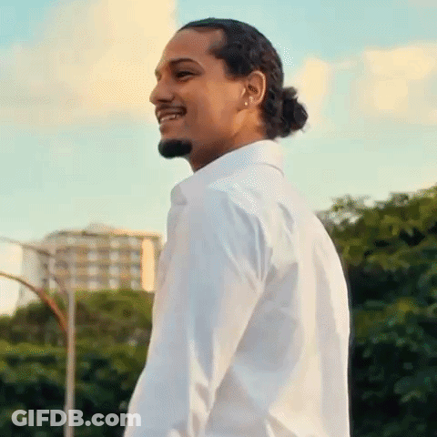 A Man Wearing A White Shirt And A Ponytail Is Smiling . GIF