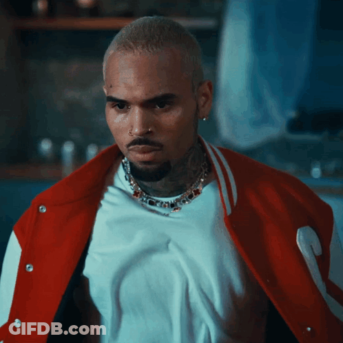A Man Wearing A White Shirt And A Red Jacket Is Looking At The Camera GIF