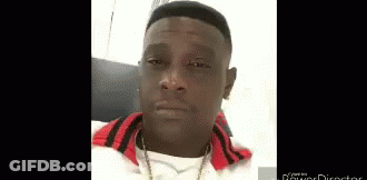 A Man Wearing A White Shirt And A Red Jacket Is Looking At The Camera . GIF