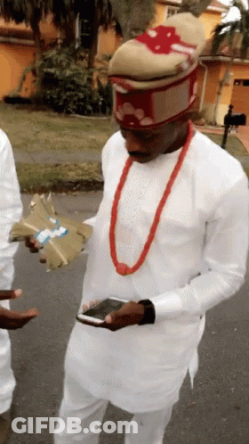 A Man Wearing A White Shirt And A Red Necklace Is Holding A Bunch Of Money GIF