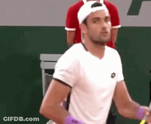 A Man Wearing A White Shirt And A White Hat Is Holding A Tennis Racket . GIF