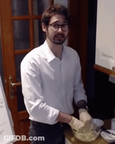 A Man Wearing A White Shirt And Gloves Is Preparing Food In A Kitchen GIF