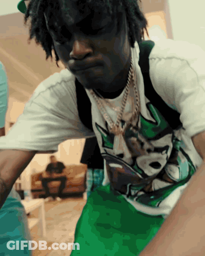 A Man Wearing A White Shirt And Green Shorts Is Looking Down GIF