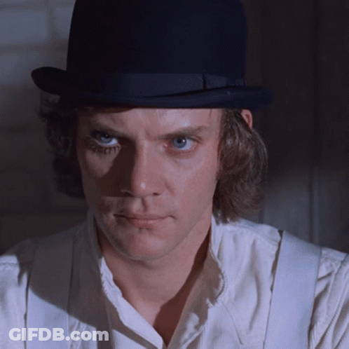 A Man Wearing A White Shirt And Suspenders Is Wearing A Black Top Hat GIF