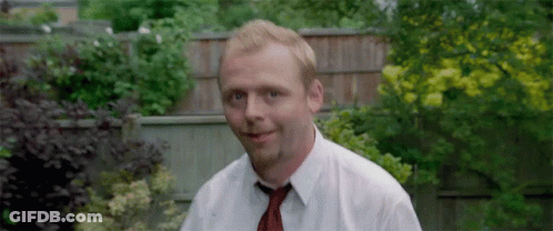 A Man Wearing A White Shirt And Tie Is Standing In A Garden . GIF