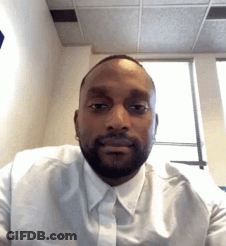 A Man Wearing A White Shirt And Tie Looks At The Camera GIF