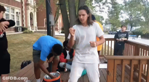 A Man Wearing A White Shirt That Says ' Almost ' On It Stands On A Deck GIF