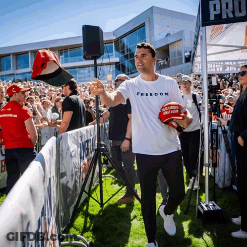 A Man Wearing A White Shirt That Says Freedom Holds A Maga Hat GIF