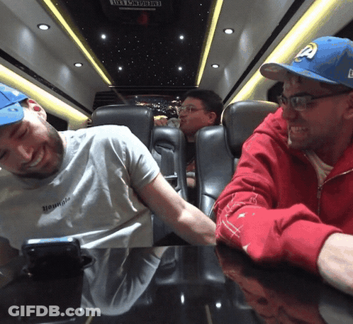 A Man Wearing A White Shirt That Says " Hounds " Sits Next To Another Man GIF