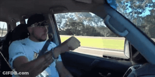 A Man Wearing A White Shirt That Says P2 On It Is Driving A Car GIF