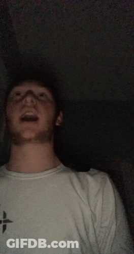 A Man Wearing A White Shirt With A Black Cross On It GIF