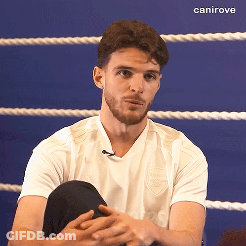 A Man Wearing A White Shirt With The Word Arsenal On It Sits In A Boxing Ring GIF