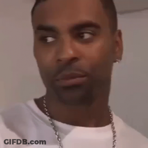 A Man Wearing A White T-Shirt And A Necklace Is Making A Funny Face . GIF