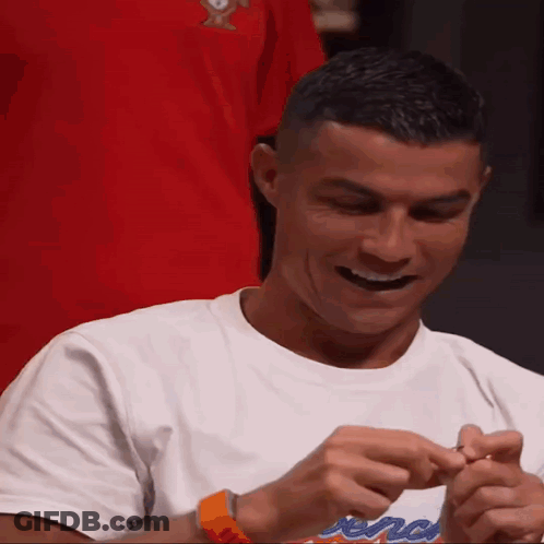 A Man Wearing A White T-Shirt With A Red Shirt Behind Him GIF