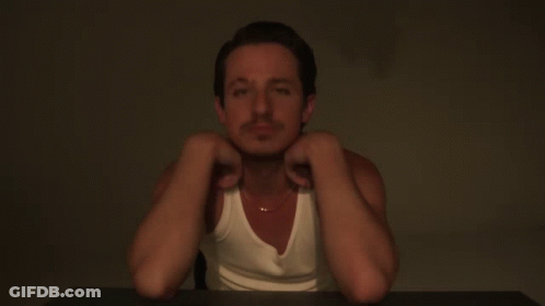 A Man Wearing A White Tank Top And A Gold Chain Around His Neck GIF
