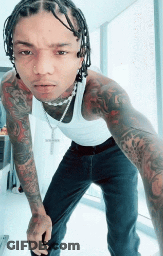 A Man Wearing A White Tank Top And A Necklace With A Cross On It GIF