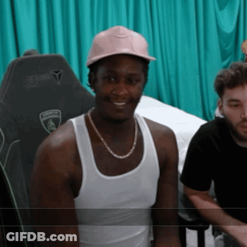 A Man Wearing A White Tank Top And A Pink Hat Has A Lamborghini Logo On His Chair GIF