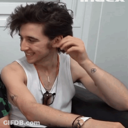 A Man Wearing A White Tank Top Has A Small Tattoo On His Arm GIF