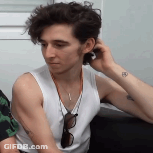 A Man Wearing A White Tank Top Has A Tattoo On His Arm GIF