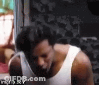 A Man Wearing A White Tank Top Is Standing In A Room . GIF