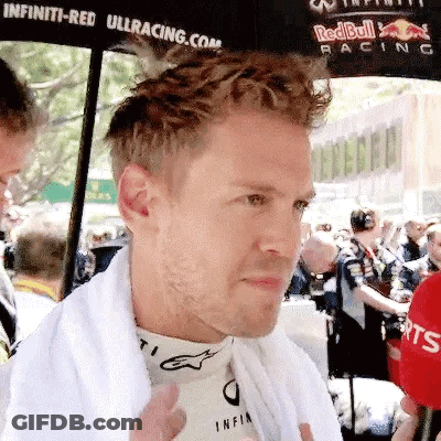 A Man Wearing A White Towel Around His Neck Is Standing In Front Of A Crowd . GIF