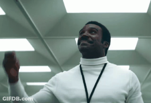 A Man Wearing A White Turtleneck And A Lanyard GIF