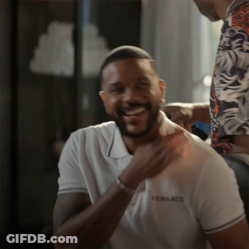 A Man Wearing A White Versace Shirt Laughs GIF