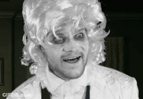 A Man Wearing A White Wig And A White Shirt Is Making A Face GIF