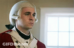 A Man Wearing A Wig And A Red Uniform Is Standing In Front Of A Window . GIF