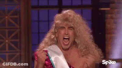 A Man Wearing A Wig And A Sash Is Screaming While Holding His Fist Up In The Air . GIF