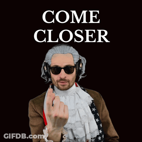 A Man Wearing A Wig And Headphones Has An American Flag Around His Waist GIF
